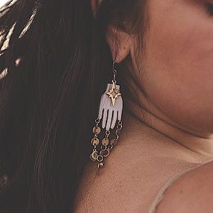 White hands dangle earrings